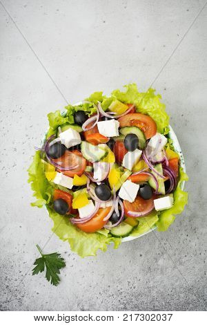 Greek salad in a ceramic plate on a white wooden background. Traditional Greek dish. Selective focus.Top view.