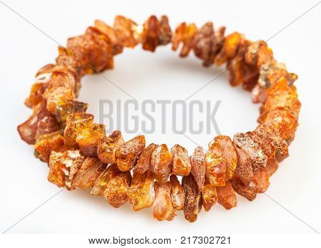 bracelet from two strings of wild amber stones on white concrete background