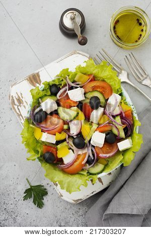 Greek salad in a ceramic plate on a white wooden background. Traditional Greek dish. Selective focus.Top view.