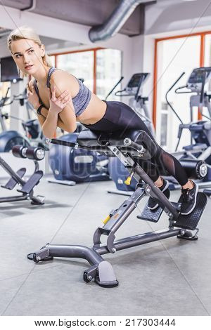 young sportive woman doing hyperextension exercise on gym machine