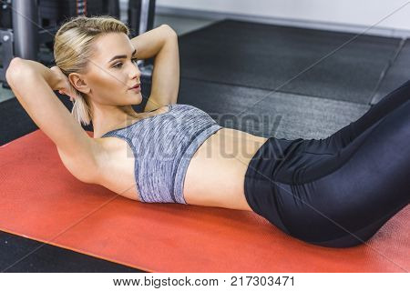 young sportive woman doing hyperextension exercise on gym machine