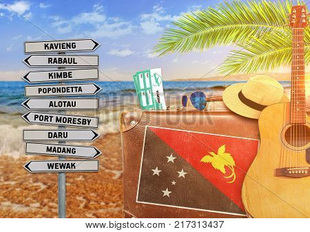 Concept of summer traveling with old suitcase and Papua New Guinea town sign