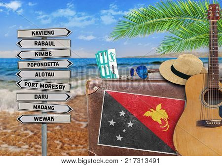 Concept of summer traveling with old suitcase and Papua New Guinea town sign