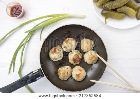 Fried dumplings in a frying pan on a light background