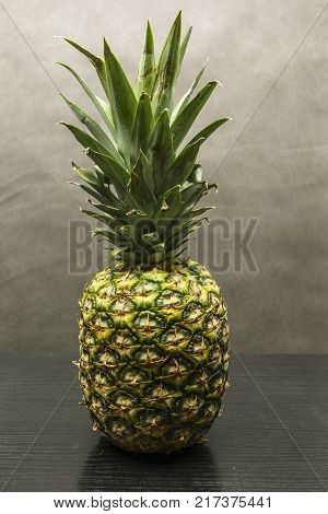A ripe pineapple fruit on a wooden table.