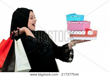 Happy young muslim woman with shopping bag and gift boxes isolated over white background.