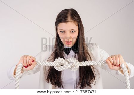 Portrait of pretty angry student or businesswoman thinking that solve a problem to untie knot over white background