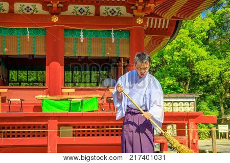 Kamakura, Japan - April 23, 2017: close-up of Shinto priest who cleans inside Tsurugaoka Hachiman Shinto shrine in the city of Kamakura, Kanagawa Prefecture.