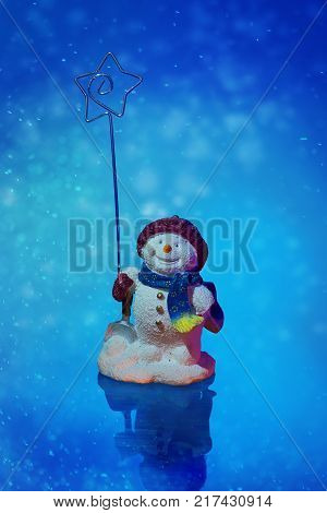 smiling snowman holds the star of bethlehem on a blue snow illustration background