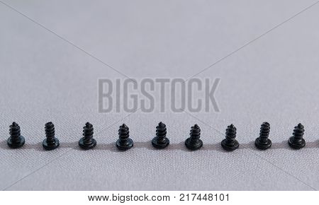 small screws arranged in a row on a gray cloth