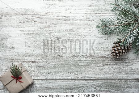 Christmas fir tree branches with gift box on white rustic wooden background with copy space for text