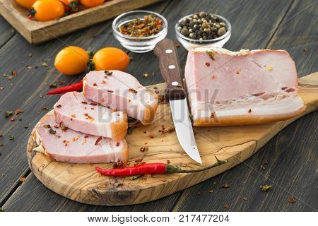 A sliced smoked brisket with spice on a dark wooden rustic background