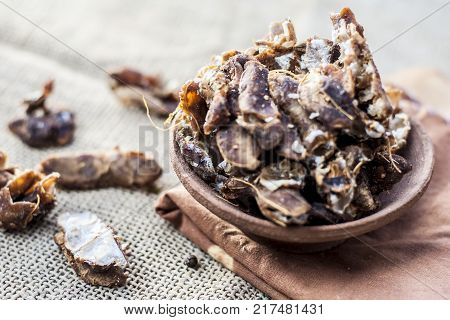 Raw Tamarindus indica,tamarind in a clay bowl on gunny background.