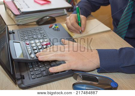 Hands of accountant with calculator and pen. Accounting background. Businessman using a calculator to calculate the numbers. Man hand with calculator at workplace office