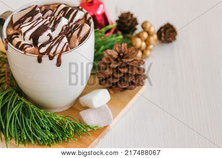 Hot chocolate in white cup top with marshmallow and chocolate sauce. Homemade hot chocolate or cacoa on wood table in top view copy space with Christmas theme background. Concept to present Christmas drink. Delicious hot chocolate ready to served.