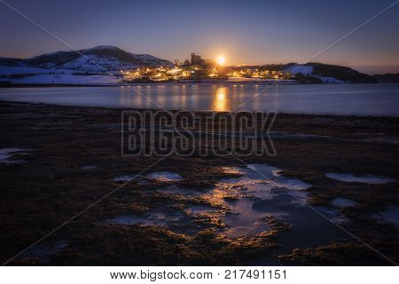 Moonset over Nanclares de Ganboa village in a frozen morning