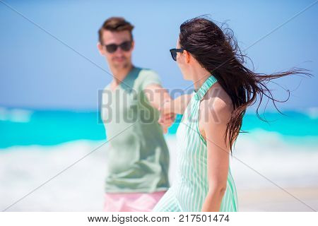 Young couple on white beach during summer vacation. Happy lovers enjoy their honeymoon at exotic island