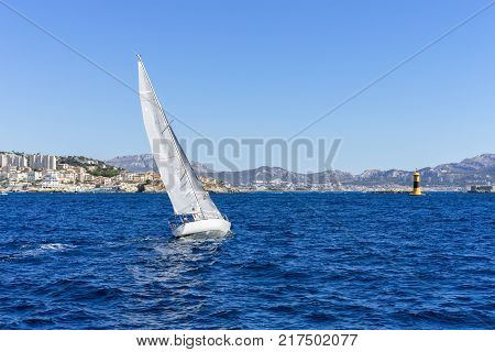 Sailing in the wind through the waves at the Sea, Marseille on background