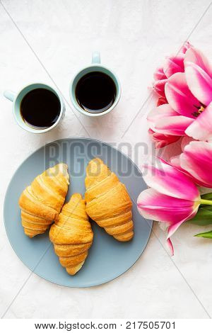 two cups of coffee, croissants and a bouquet of pink tulips, beautiful morning.