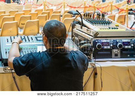 Sound technician and lights technicians control the music show in concert.Professional audio light mixer controller panel.Pro equipment for concerts.Stage lighting control.Hand adjusting audio mixer