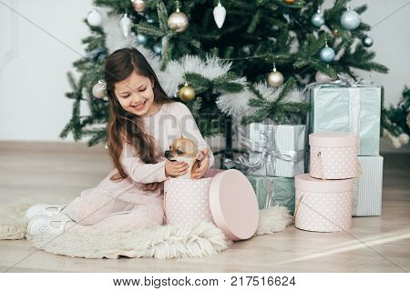 The girl sits at the tree and looks at the gifts. New Year holidays. The time to realize dreams. A gift in the box. New Year's Symbol