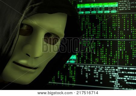The hacker in the hood and mask on the background of the digital code.