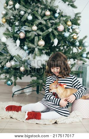 The girl sits at the tree and looks at the gifts. New Year holidays. The time to realize dreams. A gift in the box. New Year's Symbol