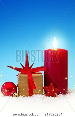 Avent candle and christmas decoration isolated on blue background. Christmas background with snow, candle and gift box .
