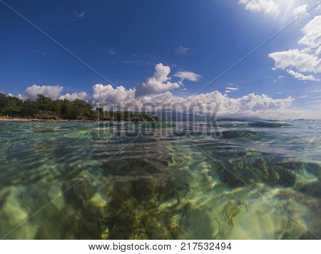 Sea water and sunny blue sky double landscape photo. Tropical seaside banner. Above and below waterline. Natural scene with ocean water surface. Still sea ripples on clean seawater. Sunny seashore