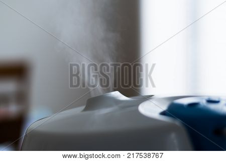Humidifier to increase room humidity in a room with windows with vapor mist.
