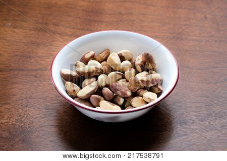 Brazil nuts in a bowl on a wooden table in the kitchen. Brazil nuts are a rich source of protein and selenium which can help hypothyroidism.