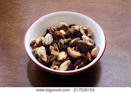 Bowl of nuts and dried fruits shot from a high angle, containing almonds, pistachios, brazil nuts, pecans, cranberries and dried cherries. Food rich in proteins, antioxidants and essential nutrients act as a healthy snack.