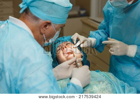 Process Of Preparing And Installing Dental Ceramic Crown. Male Professional Dentist And Female Assis