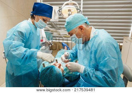 Process Of Preparing And Installing Dental Ceramic Crown. Male Professional Dentist And Female Assis