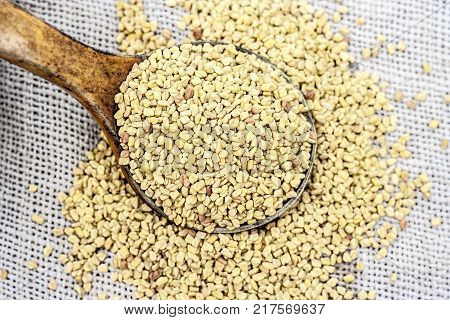 Fenugreek Seeds In A Wooden Scoop On A Gunny Background.