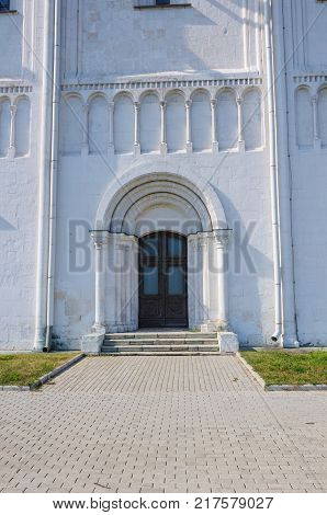 closed black wooden door in arched opening. in a stone white building