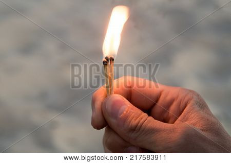 Right hand of adult man hold one match with road background.