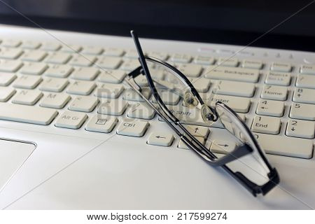 Laptop keyboard pencil and black glasses. Business concept. Selective focus.