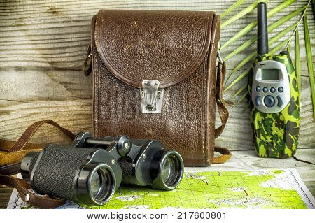 Old binoculars on wooden background with packaging and fern