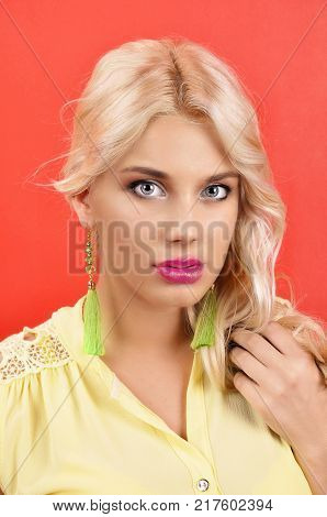 young beautiful girl in gren earrings on an red background
