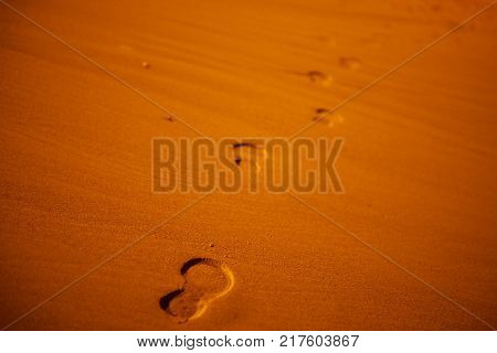 Footprints on the orange sand texture of the beach