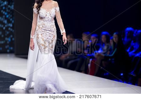 Sofia, Bulgaria - 28 September 2017: Female model walks the runway in white dress during a Fashion Show. Fashion catwalk event showing new collection of clothes. White dress.