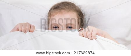 A little girl hid in bed in a medical mask to protect herself from infection
