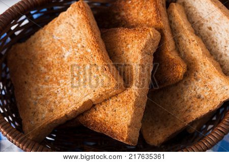 Breakfast background, white bread toasts in wicker breadbasket on checkered table napkin, closeup
