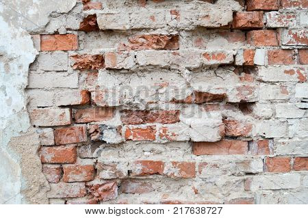 Texture of the plaster of the brick wall with old broken cracked red and white bricks. Back background.