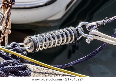 Metal cleat for mooring boats, bolted to the ground, with rope and shock absorber spring .
