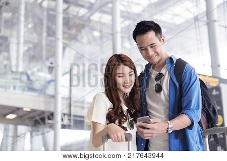 Couple asian student traveler looking or find for flight in smartphone at airport terminal. Check-in by mobile. Teenager are traveling concept.