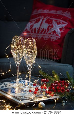 Postcard with Christmas shampagne glasses on the handmade tray over the red and white embroidered pillow with deer. Toned.