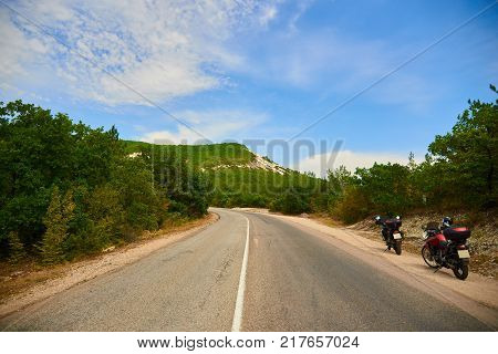 Two motorbikes on a road leading to mountain