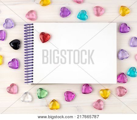 Blank notepad on spirals. Place for text. Around colored decorative hearts. Mok up